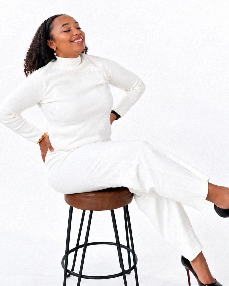 Gabrielle Maria Crawford, Esq., seated on a stool in a white outfit